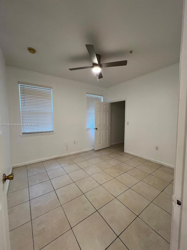 tiled spare room featuring ceiling fan