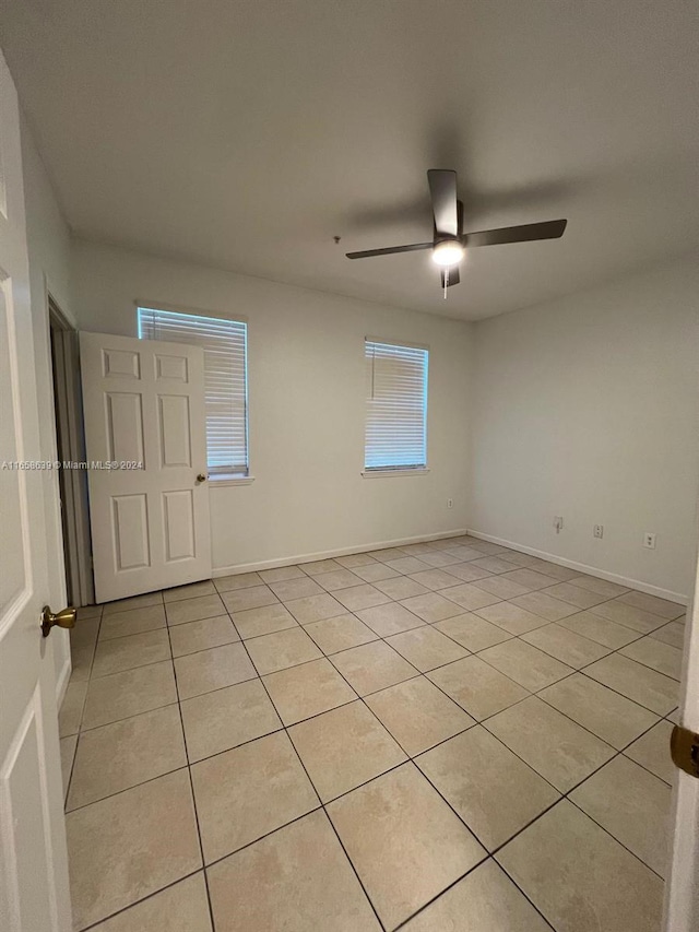 tiled empty room featuring ceiling fan and a healthy amount of sunlight