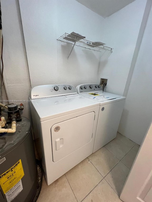 washroom with washer and clothes dryer, light tile patterned flooring, and water heater