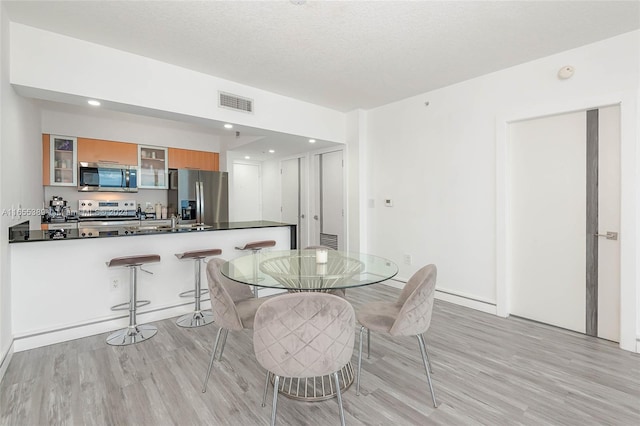 dining area with light hardwood / wood-style floors and a textured ceiling