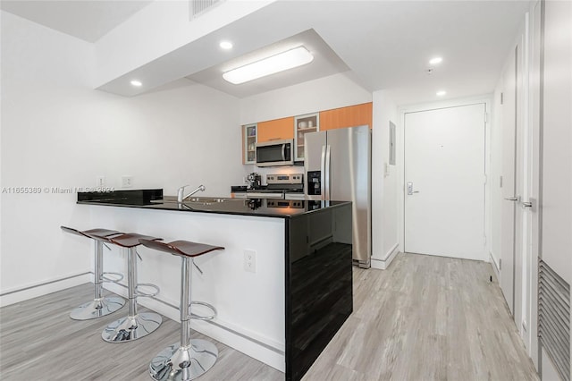 kitchen featuring sink, a breakfast bar area, light hardwood / wood-style floors, kitchen peninsula, and stainless steel appliances