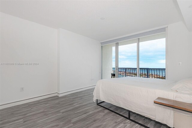 bedroom featuring dark hardwood / wood-style floors, a water view, and access to outside