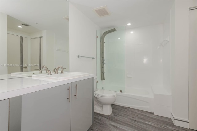 full bathroom with vanity, tiled shower / bath combo, wood-type flooring, a baseboard radiator, and toilet