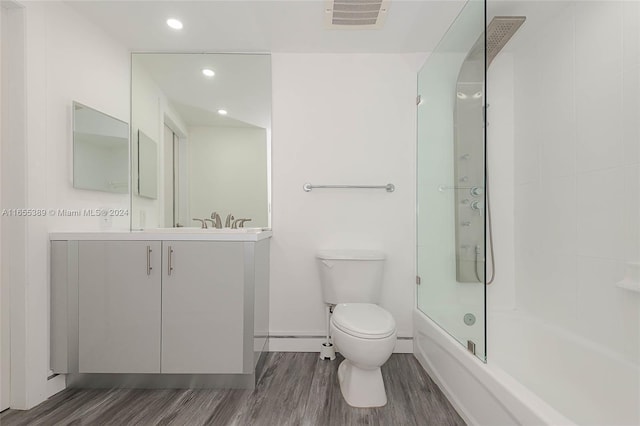 full bathroom with hardwood / wood-style flooring, vanity, toilet, and bath / shower combo with glass door