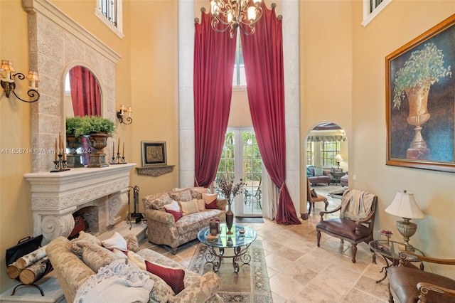 living area with an inviting chandelier, a high end fireplace, and a high ceiling