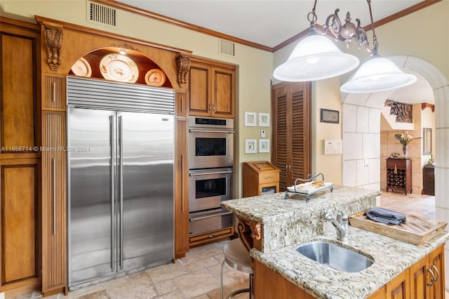 kitchen featuring light stone counters, appliances with stainless steel finishes, ornamental molding, sink, and decorative light fixtures