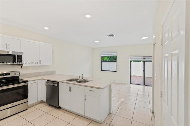 kitchen with white cabinets, light tile patterned floors, sink, kitchen peninsula, and appliances with stainless steel finishes