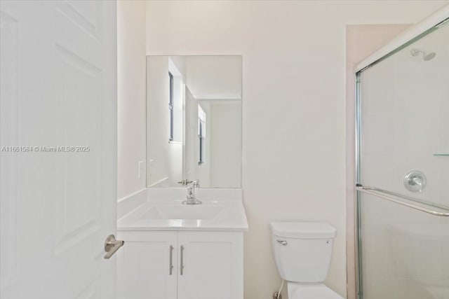 bathroom with vanity, a shower with shower door, and toilet