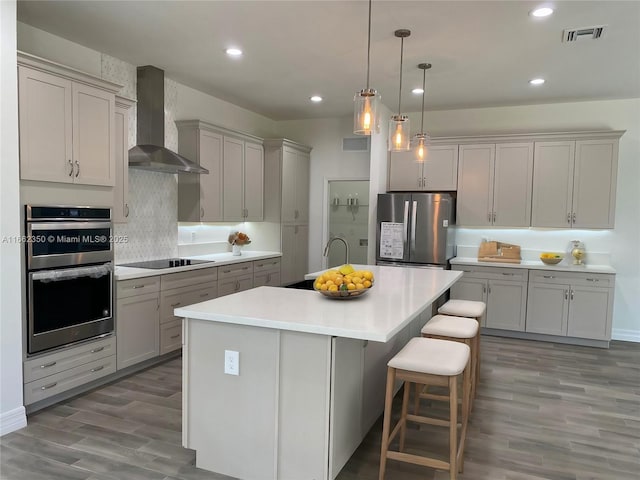 24440 SW 209th Pl, Homestead, FL 33031 - kitchen featuring appliances with stainless steel finishes, wall chimney exhaust hood, a sink, wood finished floors, and a center island with sink