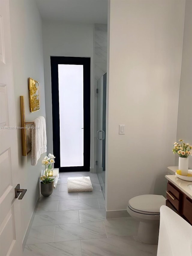 bathroom featuring vanity, toilet, and a shower with door