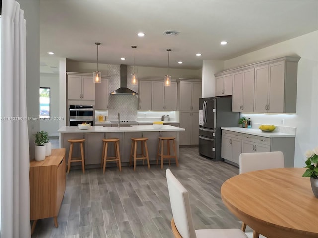 kitchen with wood-type flooring, wall chimney exhaust hood, and gray cabinetry