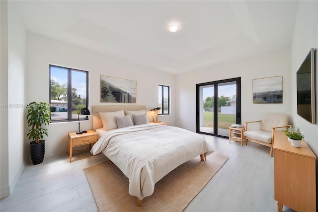 bedroom featuring multiple windows, access to outside, and light wood-type flooring