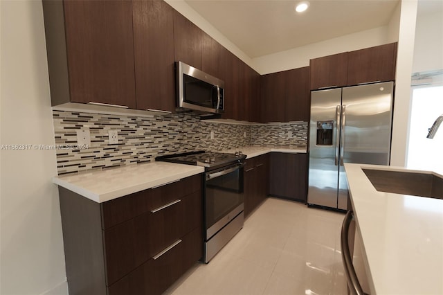 kitchen with appliances with stainless steel finishes, tasteful backsplash, light tile patterned floors, dark brown cabinets, and sink