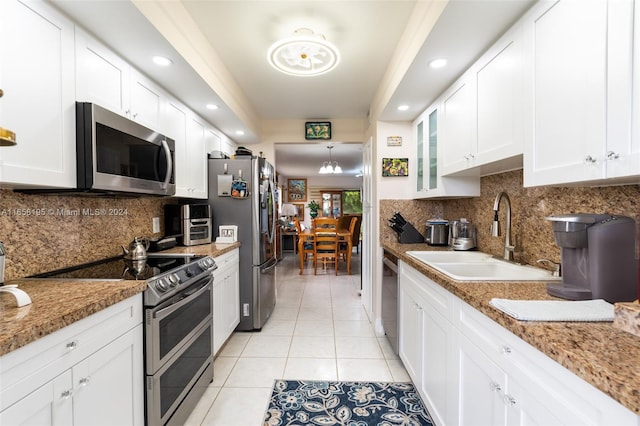 kitchen featuring stainless steel appliances, white cabinets, stone countertops, and sink