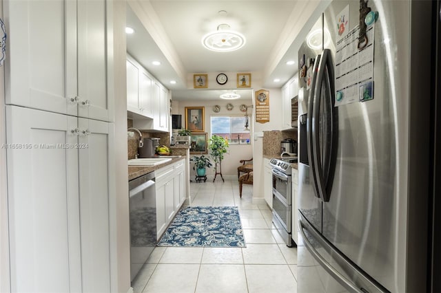 kitchen featuring white cabinets, backsplash, light tile patterned floors, stainless steel appliances, and sink