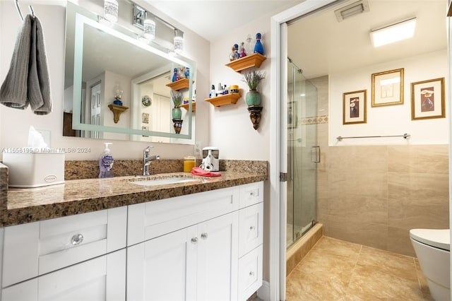 bathroom with walk in shower, vanity, tile patterned flooring, and toilet