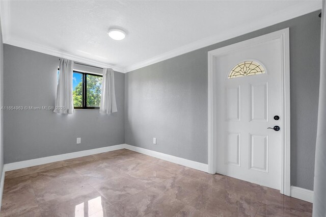 foyer with a textured ceiling and crown molding