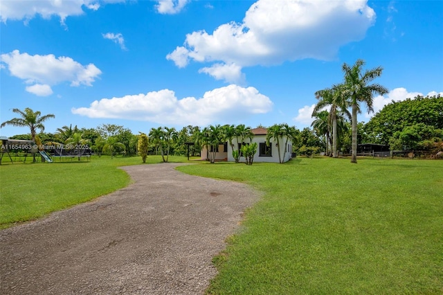 view of home's community with driveway, playground community, and a yard