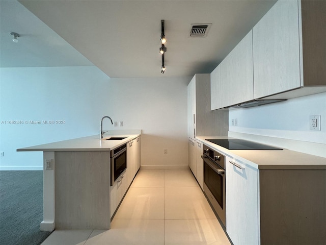 kitchen with black electric stovetop, oven, sink, and kitchen peninsula