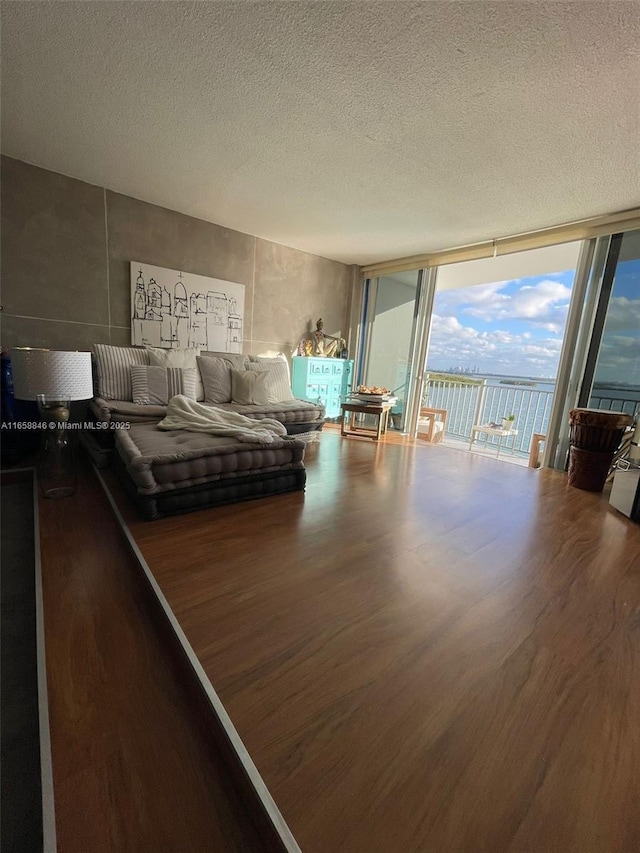 unfurnished bedroom featuring access to outside, a textured ceiling, floor to ceiling windows, and hardwood / wood-style flooring