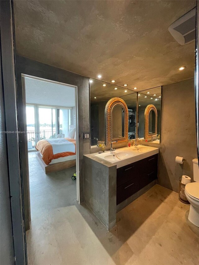 bathroom featuring toilet, vanity, and concrete floors