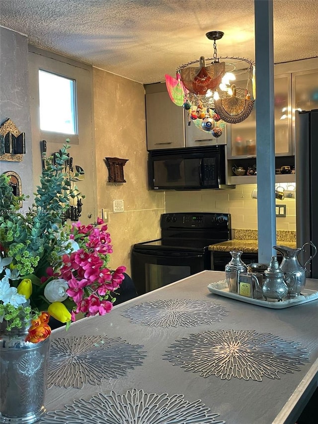 kitchen with a textured ceiling, backsplash, and black appliances