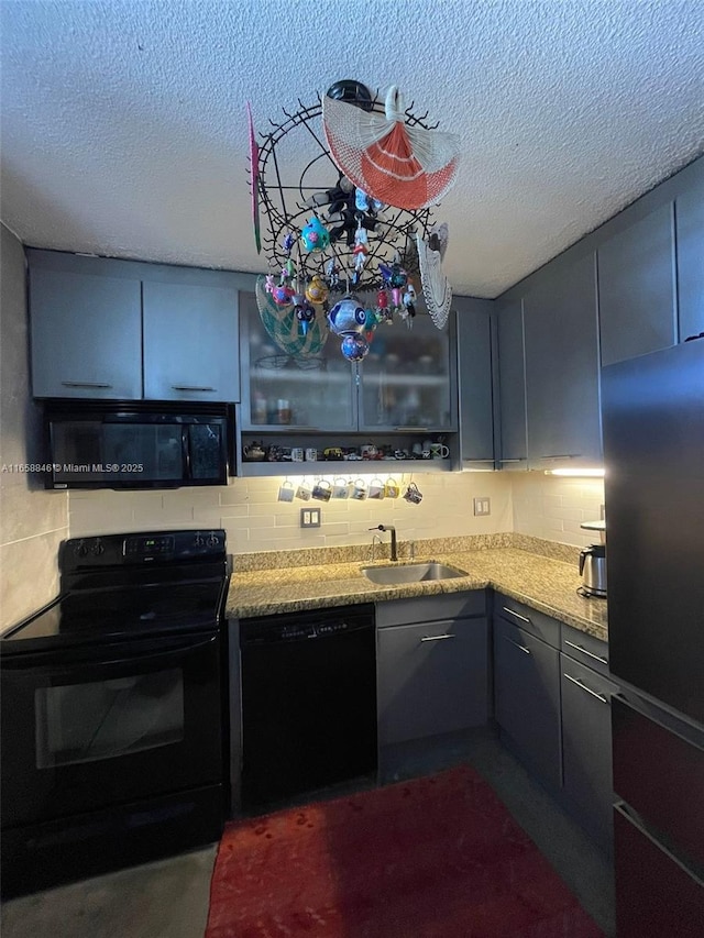 kitchen featuring black appliances, light stone countertops, sink, and a textured ceiling