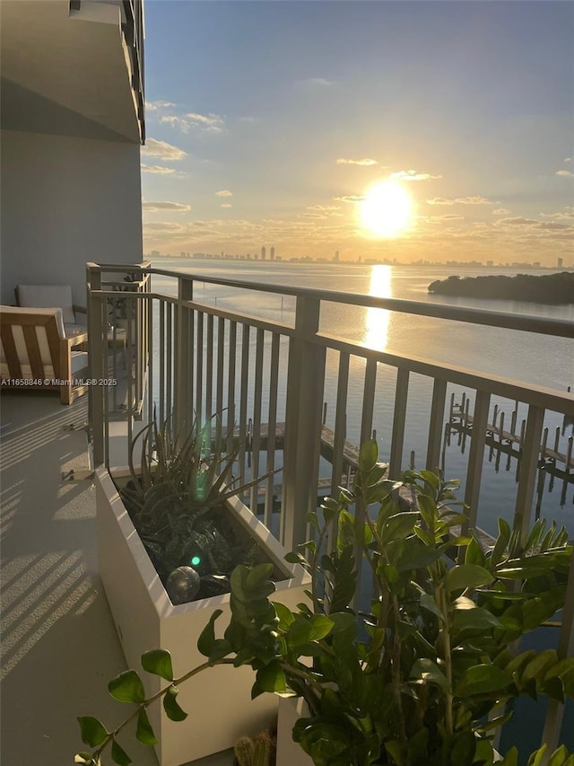 balcony at dusk featuring a water view