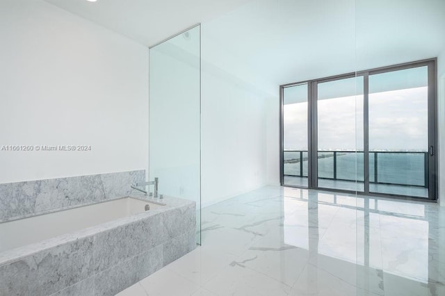 bathroom featuring tiled tub and expansive windows