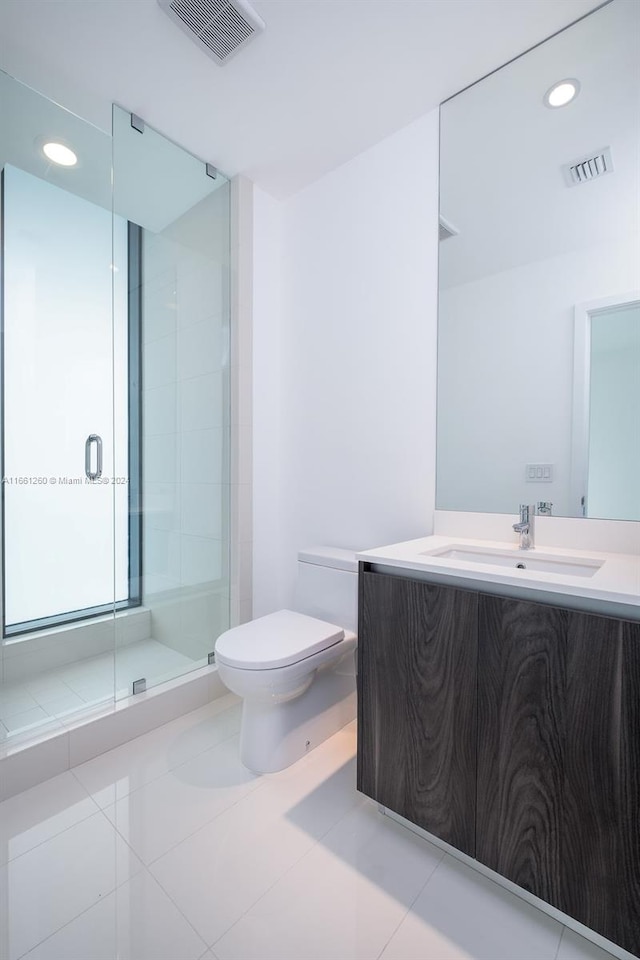 bathroom with vanity, toilet, tile patterned floors, and a shower with door