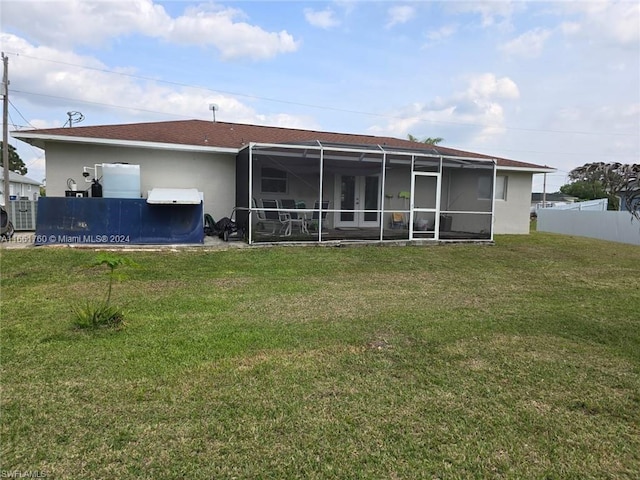 rear view of property with a lanai and a yard