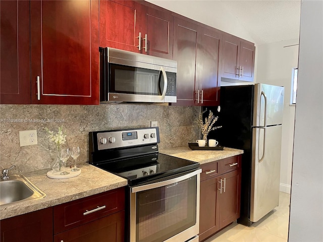 kitchen featuring lofted ceiling, light tile patterned floors, sink, stainless steel appliances, and decorative backsplash