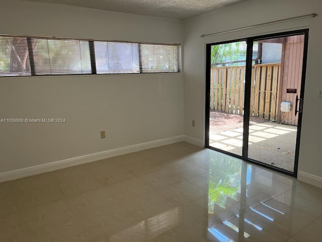 unfurnished room featuring a textured ceiling and tile patterned flooring