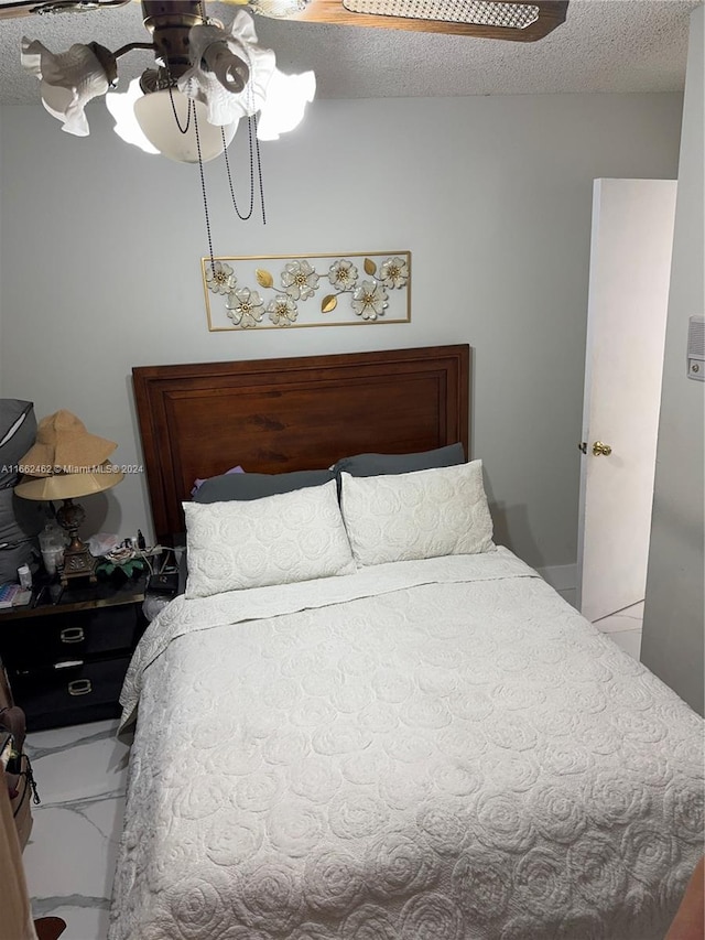 bedroom with ceiling fan and a textured ceiling