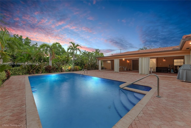 pool at dusk with a patio area