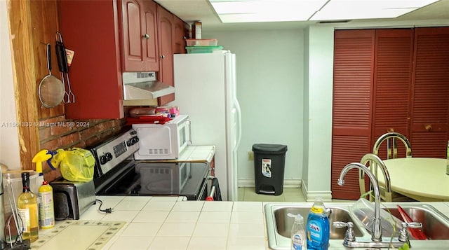 kitchen featuring tile counters, sink, electric range, and exhaust hood