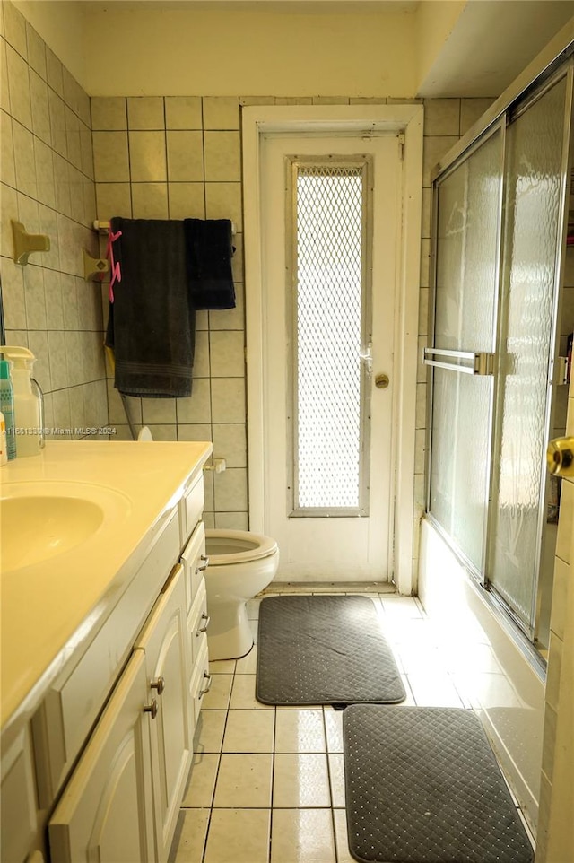 full bathroom with tile walls, vanity, tile patterned flooring, a healthy amount of sunlight, and toilet