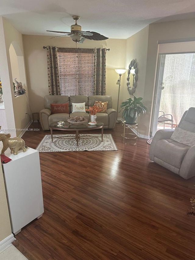 living room featuring dark wood-type flooring and ceiling fan