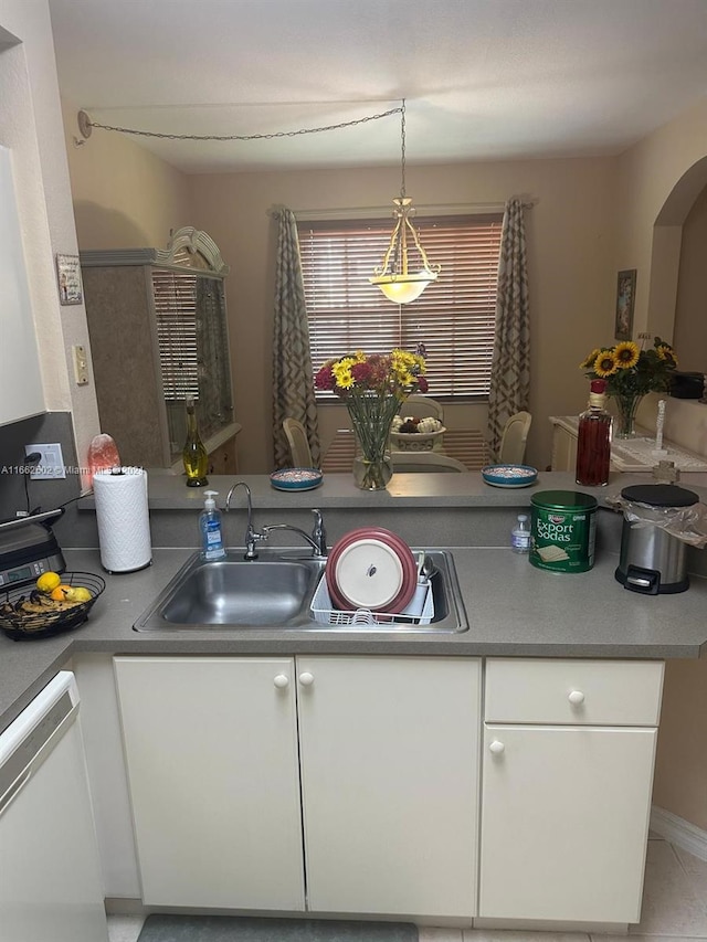 kitchen featuring sink, white cabinetry, hanging light fixtures, light tile patterned floors, and white dishwasher