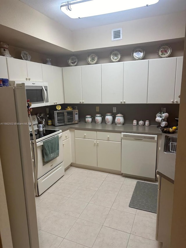 kitchen with white appliances, sink, light tile patterned floors, and white cabinets