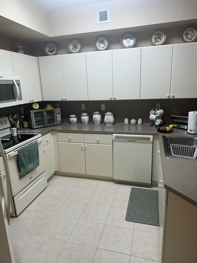 kitchen with white cabinets, white appliances, light tile patterned floors, and sink