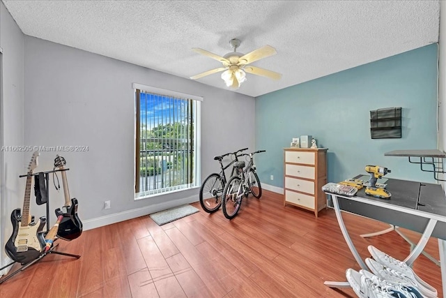 workout room with a textured ceiling, light hardwood / wood-style floors, and ceiling fan