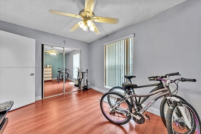 workout room featuring a textured ceiling, hardwood / wood-style flooring, and ceiling fan