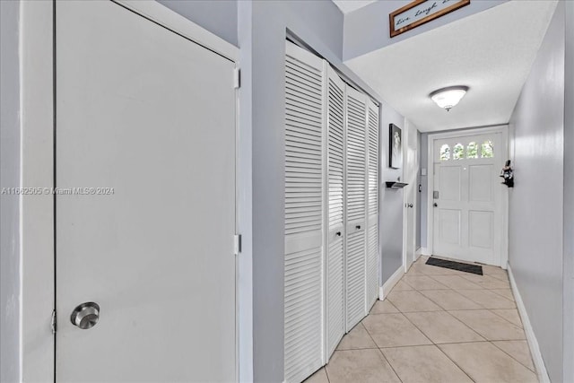 doorway to outside featuring a textured ceiling and light tile patterned floors