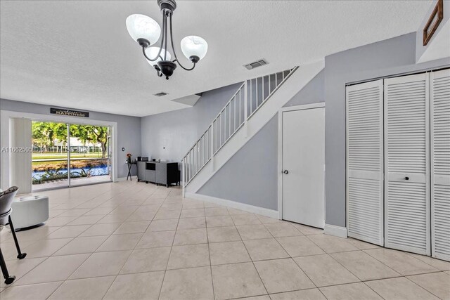 unfurnished living room featuring light tile patterned flooring, a notable chandelier, and a textured ceiling