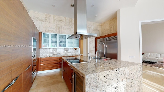 kitchen with built in refrigerator, island exhaust hood, a large island with sink, beverage cooler, and black electric cooktop