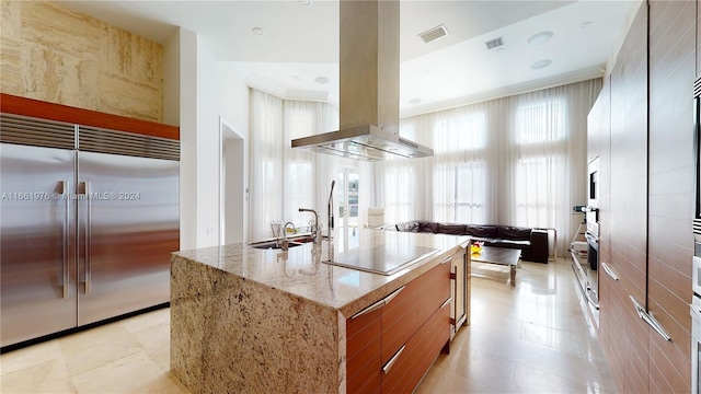1486 Commodore Way, Hollywood, FL 33019 - kitchen with built in refrigerator, black electric cooktop, island range hood, brown cabinetry, and modern cabinets