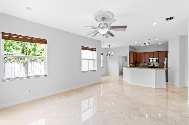 unfurnished living room with ceiling fan with notable chandelier