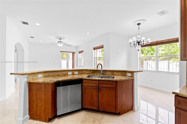 kitchen featuring dishwasher, sink, hanging light fixtures, a kitchen island with sink, and light stone countertops