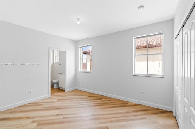 unfurnished bedroom with connected bathroom, a closet, and light wood-type flooring